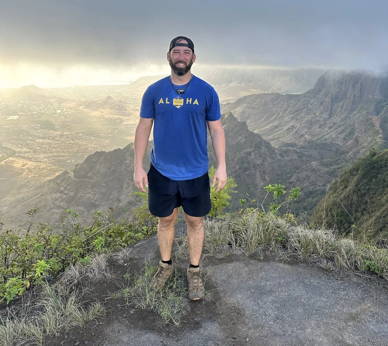 Ryan Adams on a mountain summit with ridges behind him