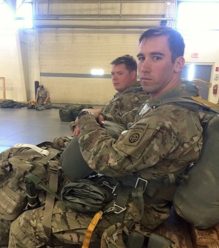 Ryan Adams seated with parachute equipment in a hangar