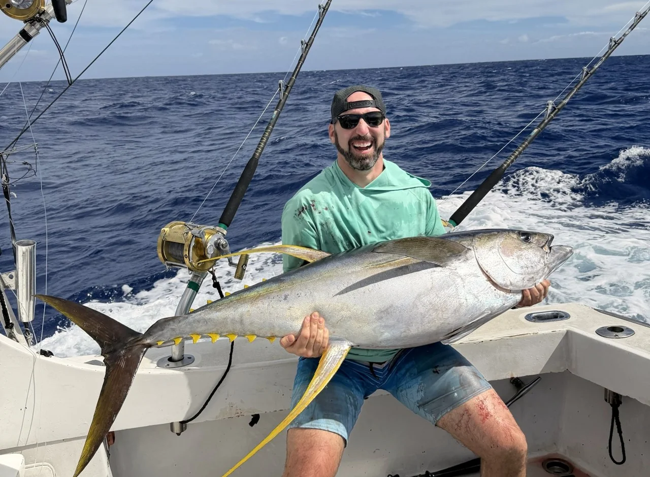Ryan Adams holding a yellowfin tuna on a fishing boat